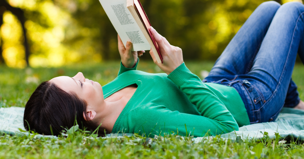 Woman reading a book and lying on the grass