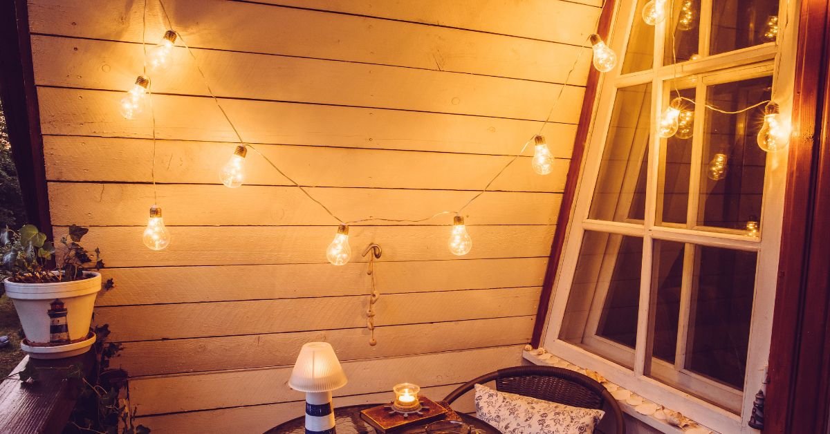 Cozy balcony corner decorated with warm string lights, creating a relaxing atmosphere in a small urban balcony garden setting.