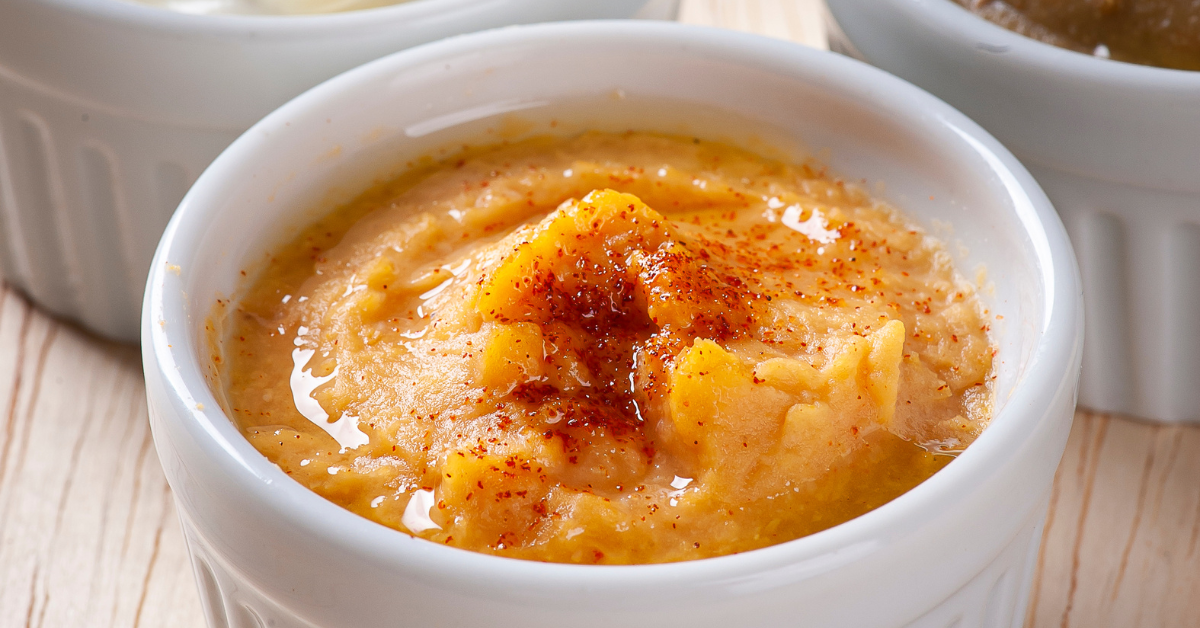 Chickpea paste in a white bowl, sprinkled with red spice.
