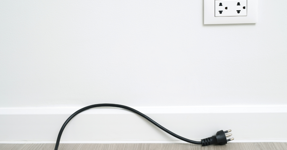 the cable plug disconnected from the power socket on the white wall
