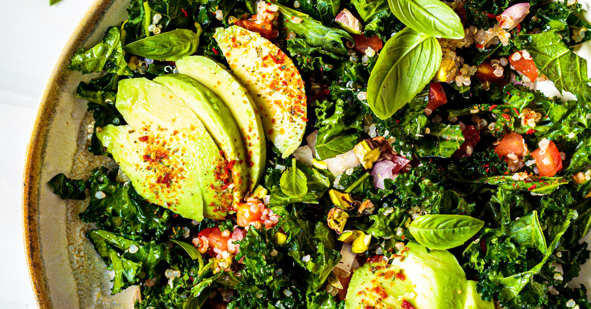 A bowl full of kale and avocado, sprinkled with spices.