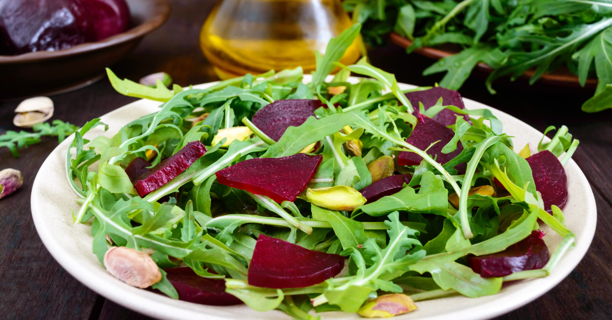 Plate with arugula and slices of beetroot quarters.